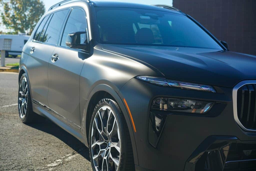 Low front angle of a BMW X7 M60i showing the satin finish of STEK DYNOmatte Black paint protection film