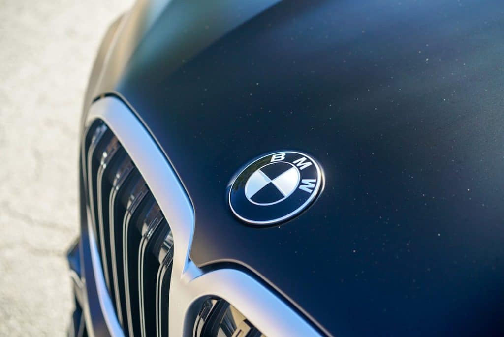 Close-up of the BMW roundel and kidney grille on a hood covered in STEK DYNOmatte Black PPF